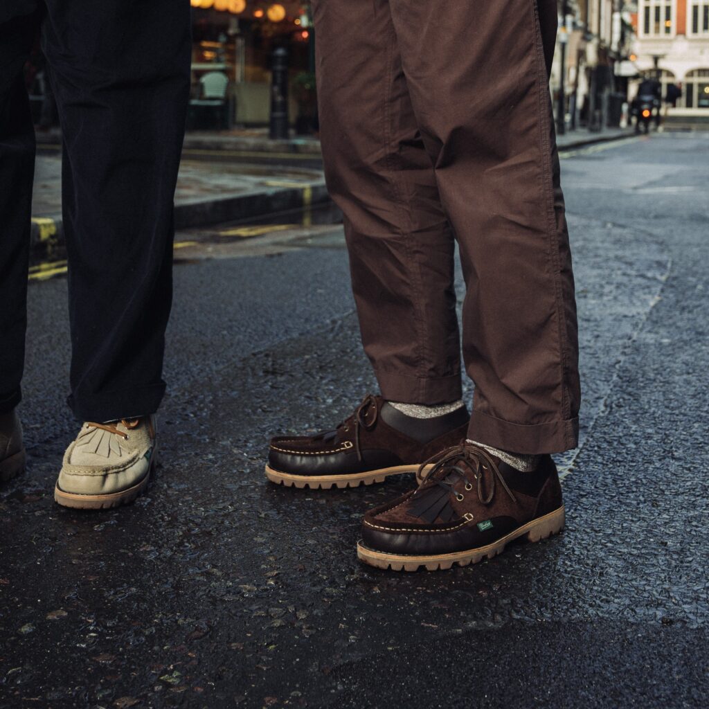 Deux hommes portant les chaussures Paraboot Thiers x Universal Works en coloris Sand et Café, marchant dans une rue.