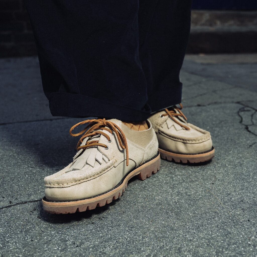Détail des chaussures Paraboot Thiers Sand en cuir beige clair portées avec un pantalon sombre sur un trottoir.