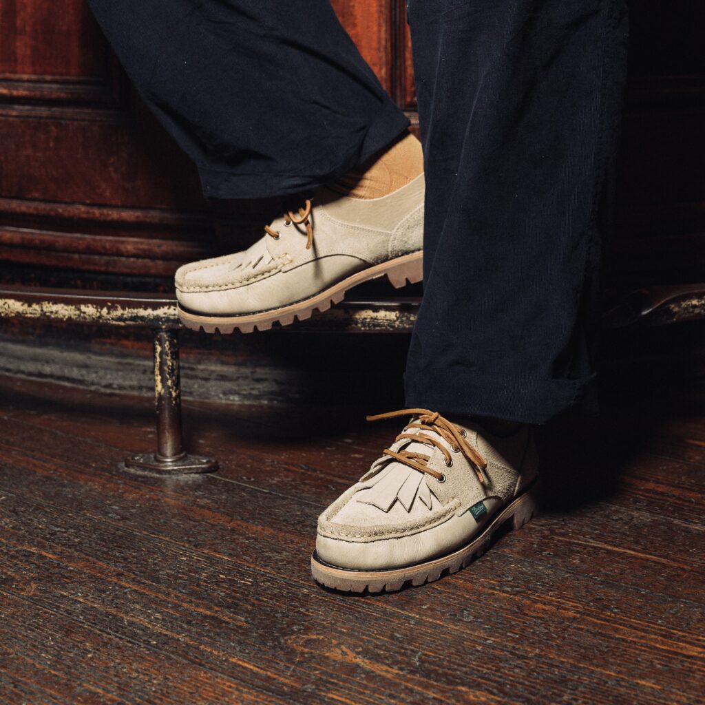 Détail des chaussures Paraboot Thiers Sand en cuir beige clair portées avec un pantalon sombre sur un trottoir.