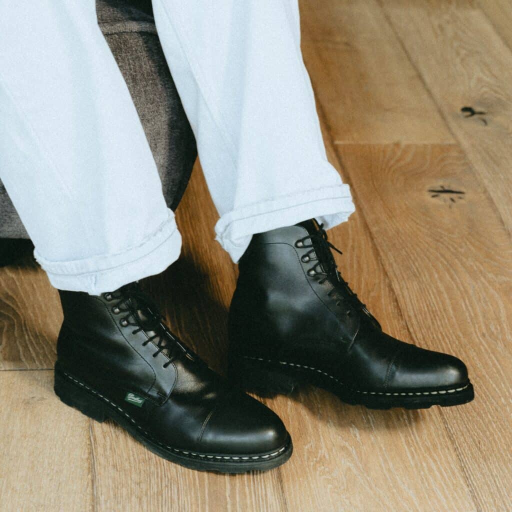 Femme portant des bottines à lacets Paraboot modèle Clamart noir avec une jupe et un pull marin.
