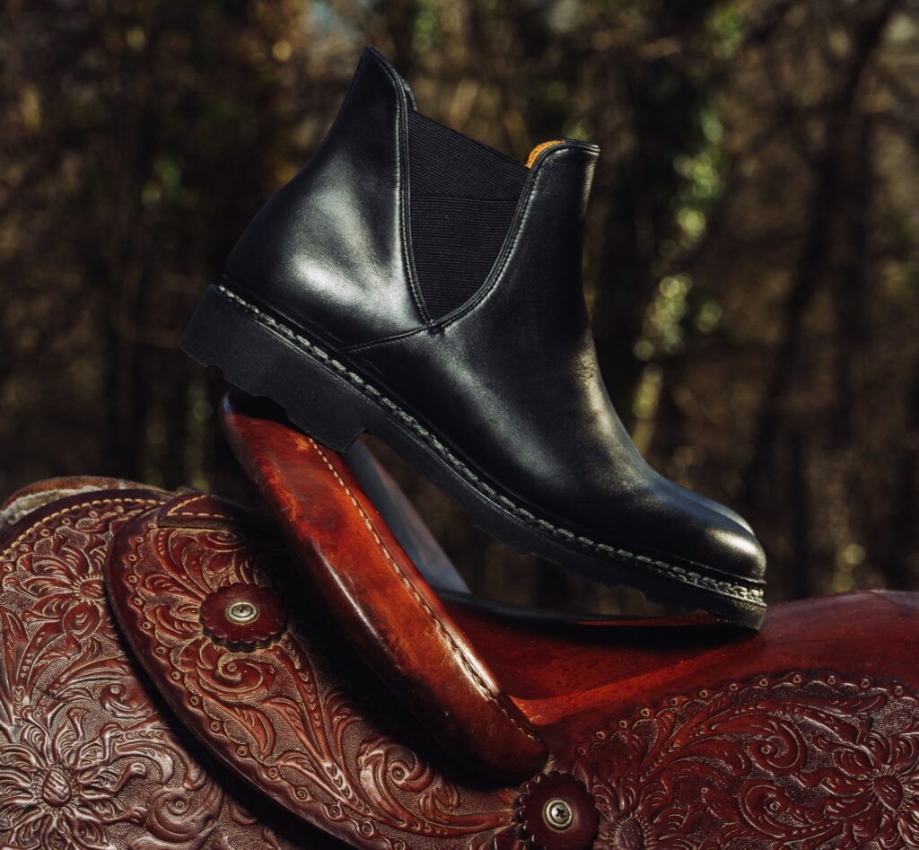 Chelsea boots femme noires Paraboot modèle Valdaine portées dans un champ avec montagnes au loin.