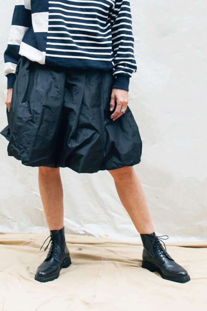 Femme portant des bottines à lacets Paraboot modèle Clamart noir avec une jupe et un pull marin.