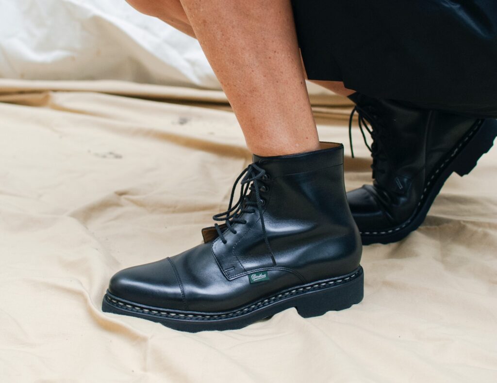 Femme portant des bottines à lacets Paraboot modèle Clamart noir avec une jupe et un pull marin.