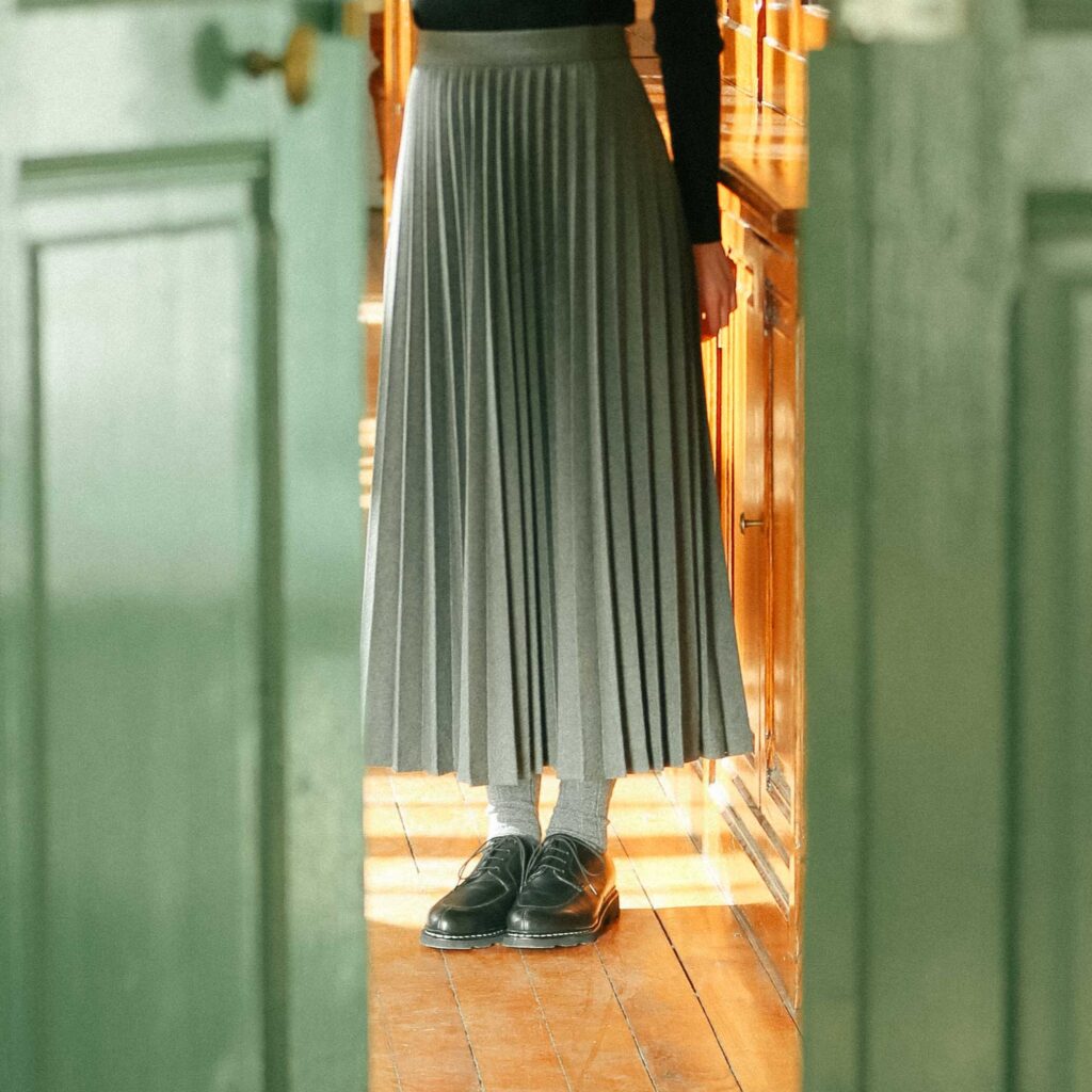 Chaussures Paraboot Veley en cuir lisse noir à bout chasse, portées avec une jupe plissée grise et des chaussettes en laine.