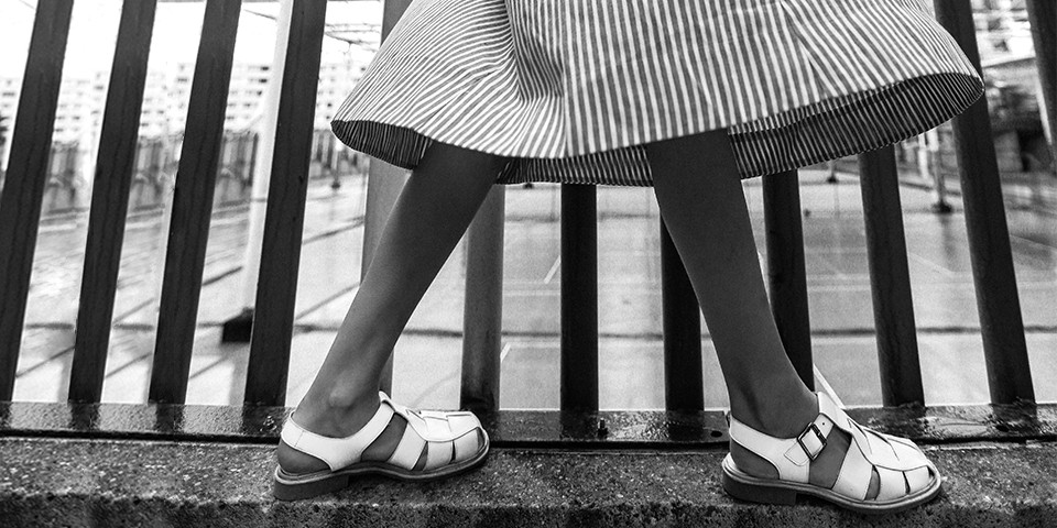 Sandales femme en cuir blanc Paraboot portées avec une robe rayée pour un look urbain.