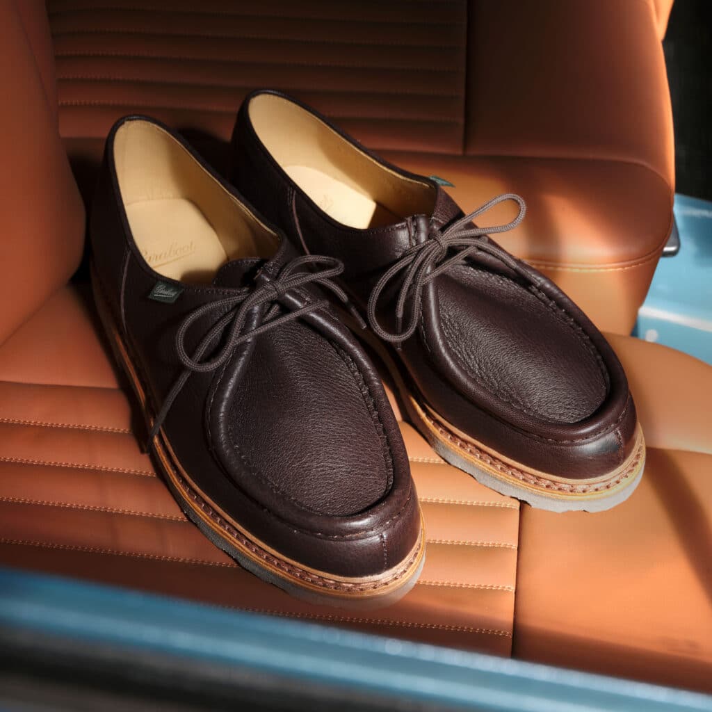 Paire de chaussures Paraboot marron posée sur les sièges en cuir d'un véhicule de collection.