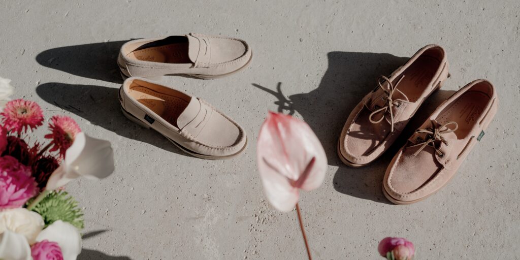 Chaussures été femme : vue de dessus d'une personne portant un mocassin Coraux mocassin Coraux en velours crème et la chaussure bateau barth en velours nude Paraboot entre des pots de fleurs colorées.