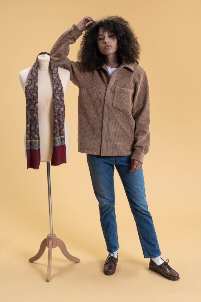Portrait d'une femme portant des chaussures bateau Barth de Paraboot en cuir lisse America, associées à un jean bleu et une chemise en velours côtelé marron.