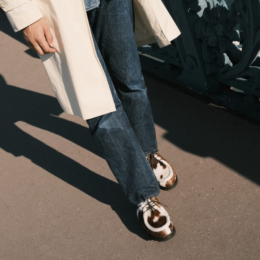 Modèle iconique Michael de Paraboot en cuir façon poils de vache marron et blanc, porté avec un jean brut et un manteau clair pour un look urbain élégant.