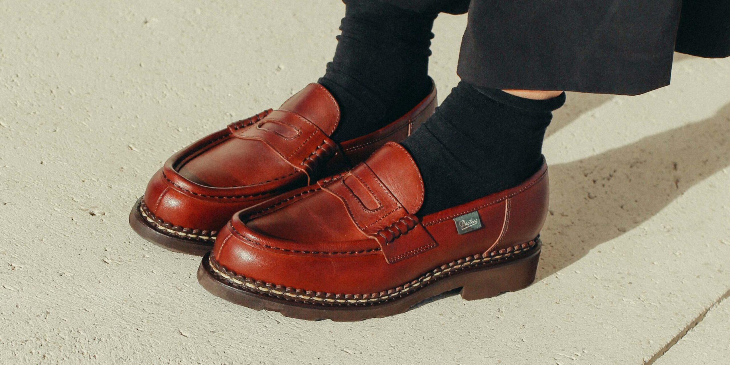 Paire de mocassins Paraboot Orsay pour femme en cuir lisse marron avec montage cousu Norvégien et semelle gomme, portés avec des chaussettes noires.