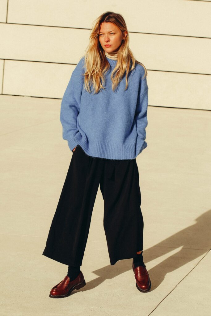 emme portant des mocassins Paraboot Orsay en cuir marron avec un pull bleu et un pantalon noir large, pour une allure citadine élégante.