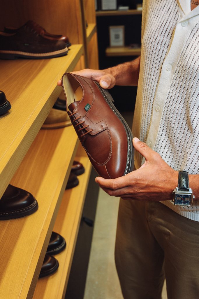 Gros plan sur les mains d'un homme découvrant le derby Paraboot Avignon en cuir lisse marron en boutique.