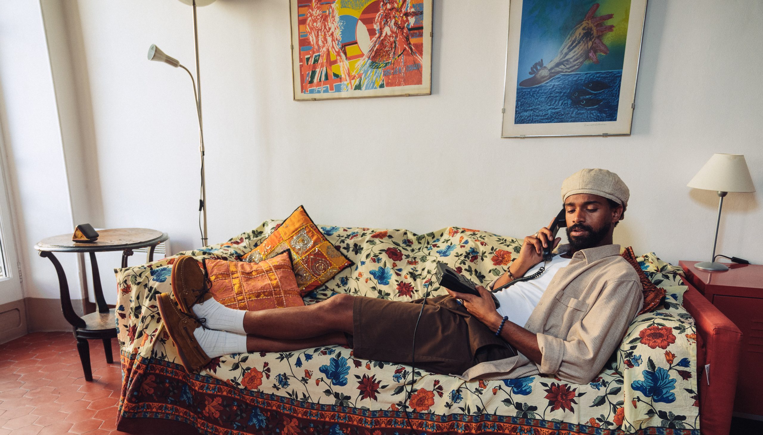 Un uomo sdraiato su un divano vintage indossa scarpe da barca Paraboot Barth in suede color cuoio.