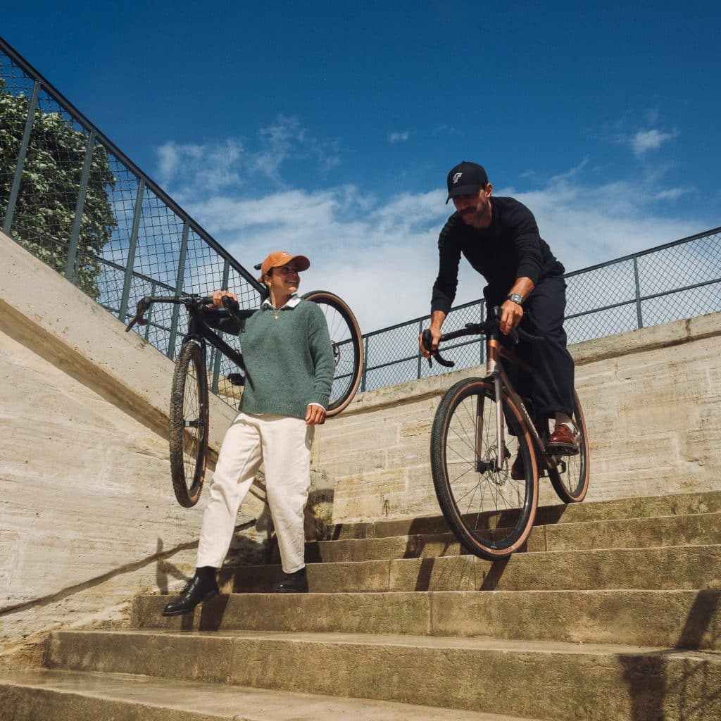 Homme et femme descendant un escalier en pierre à vélo aux Tuileries avec des derbies Paraboot marron et noirs.