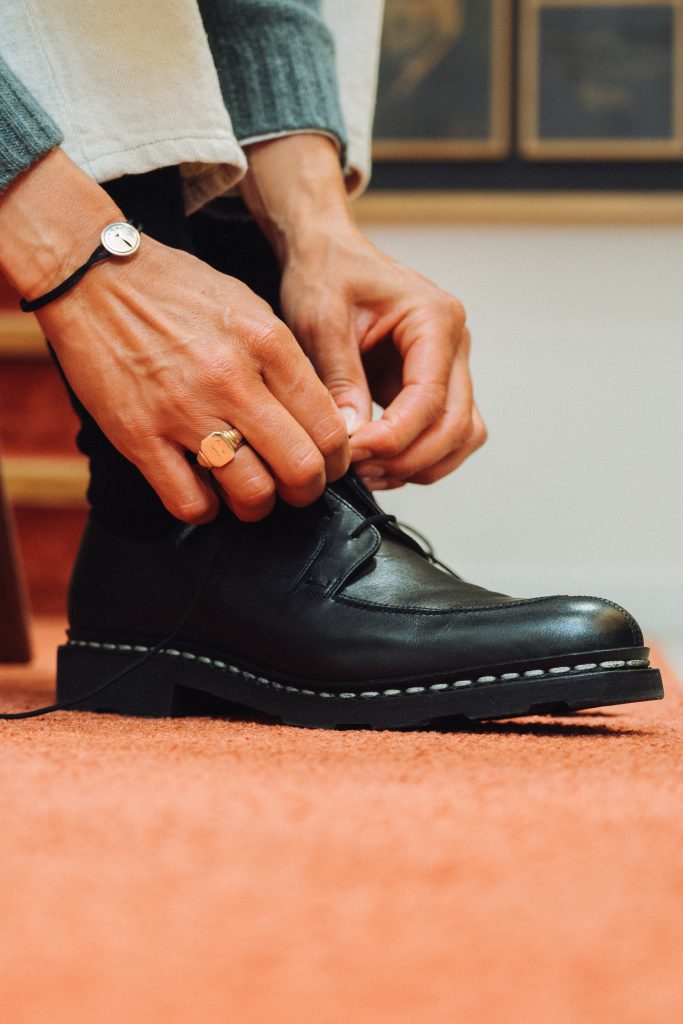 Femme laçant son derby en cuir lisse noir Paraboot Veley avec semelle crantée.