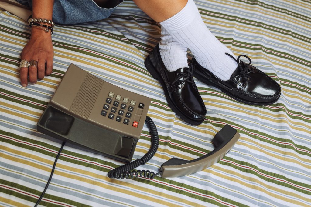 Chaussures bateau Malo Paraboot en cuir brillant noir et semelle gomme portées avec chaussettes blanches.