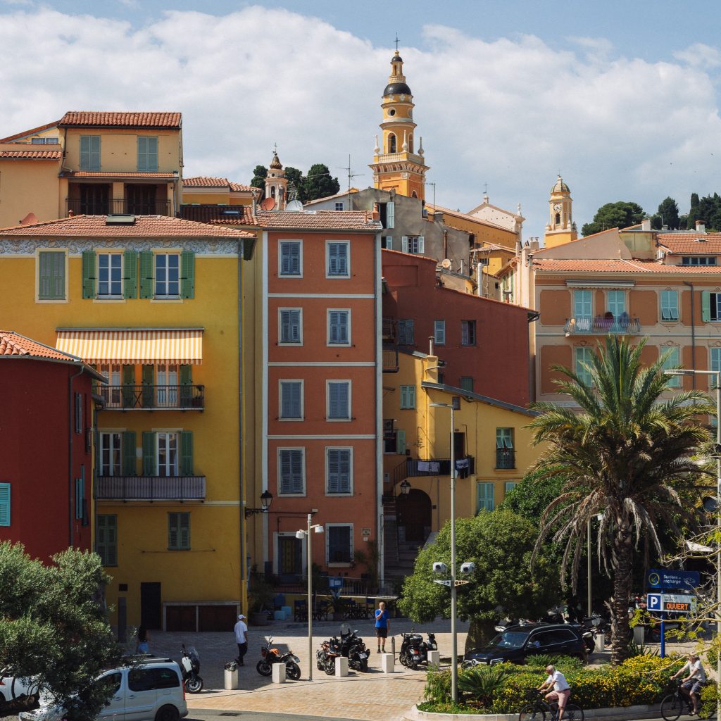 Façades colorées ocre et jaune et clocher typique de la vieille ville de Menton. Flânerie architecturale entre les murs colorés et l'histoire de la cité mentonnaise.