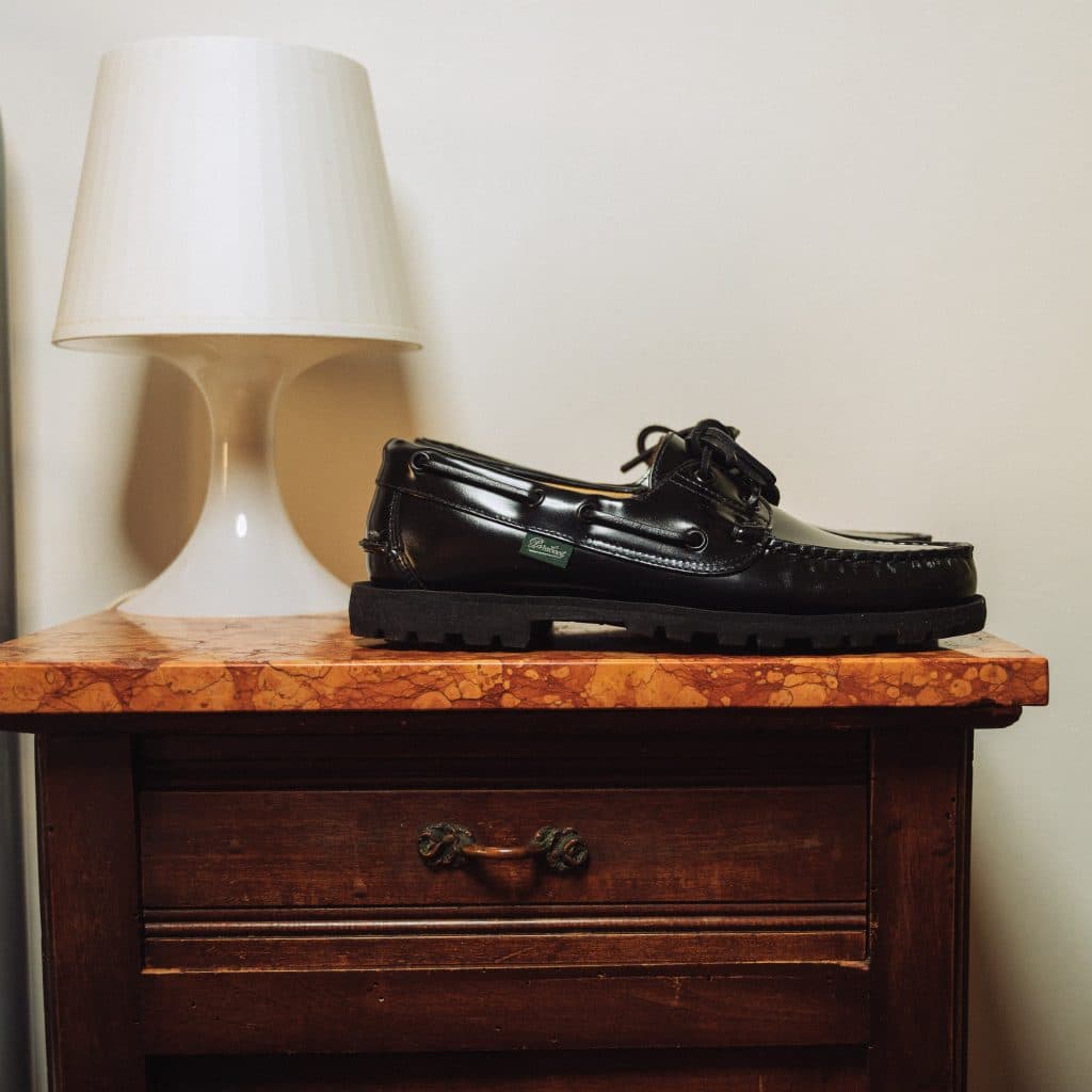 Chaussure bateau femme Malo Paraboot en cuir brillant noir sur console en marbre.