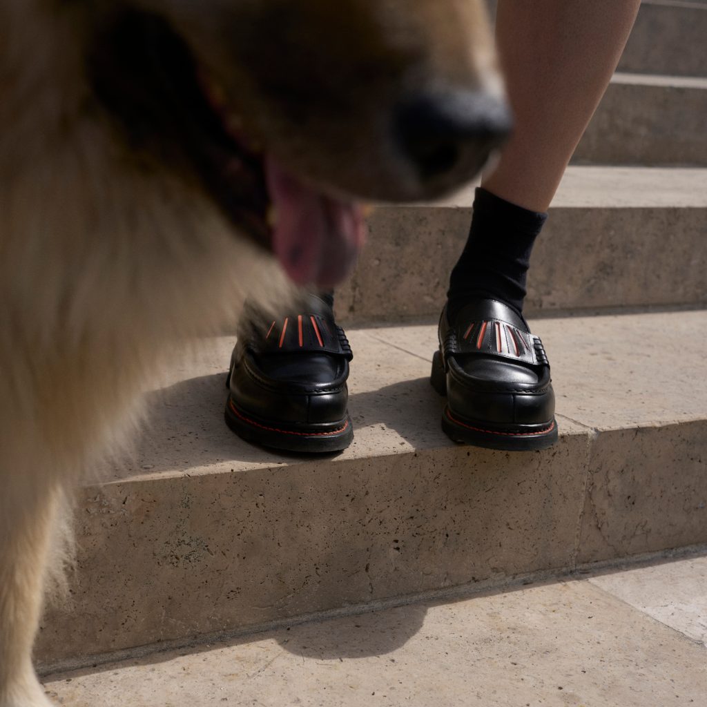 Gros plan sur les mocassins Orsay noirs Paraboot avec le détail French Plissé Camille Fournet, portés sur des marches en pierre.
