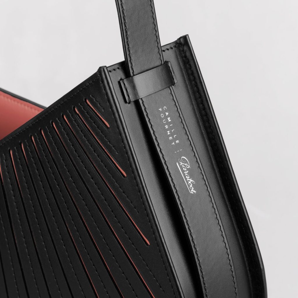 Gros plan sur le logo argenté de la collaboration Camille Fournet et Paraboot sur la bride du sac Balancier MM.